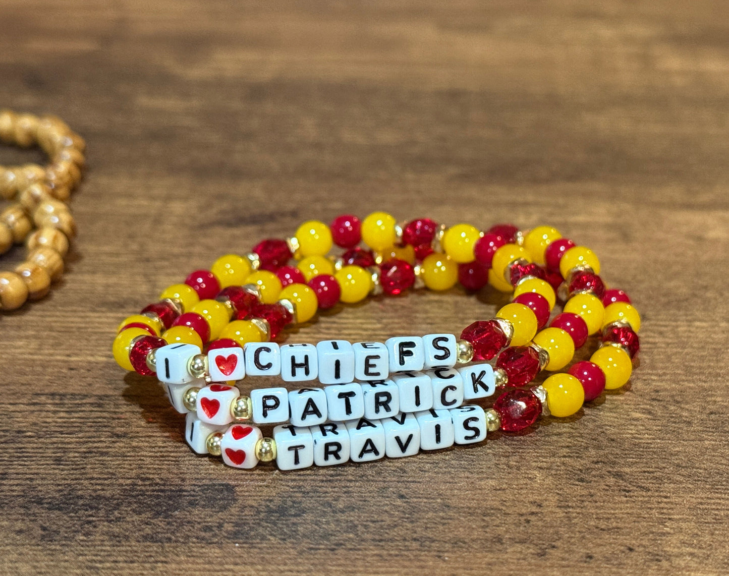 Beaded bracelet with customizable name charms on a wooden surface