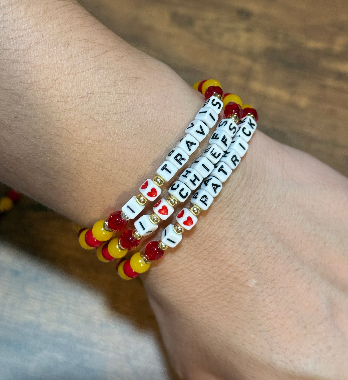 Bracelet with letter beads on a wrist against a wooden background