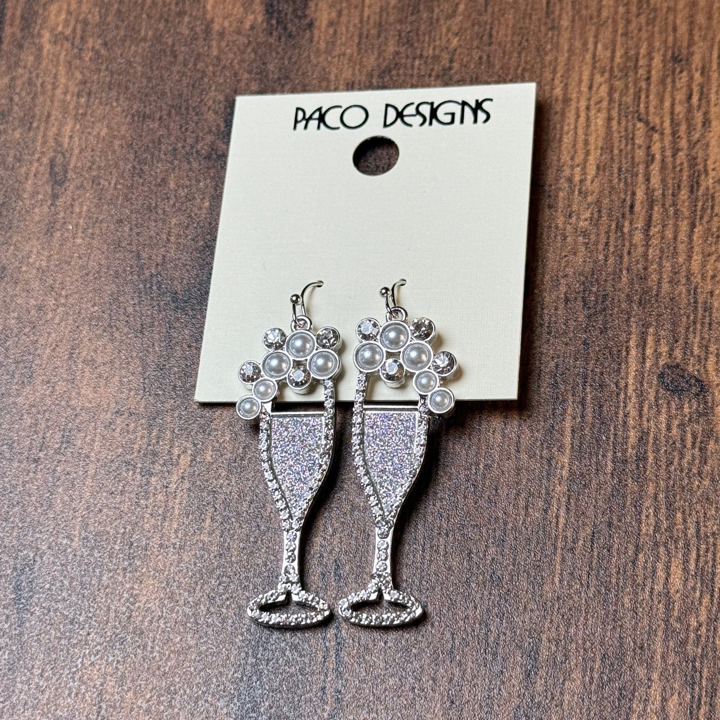 Silver earrings on a Paco Designs card against a wooden background
