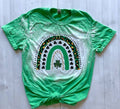 Green t-shirt with a rainbow and shamrock design on a light wooden surface