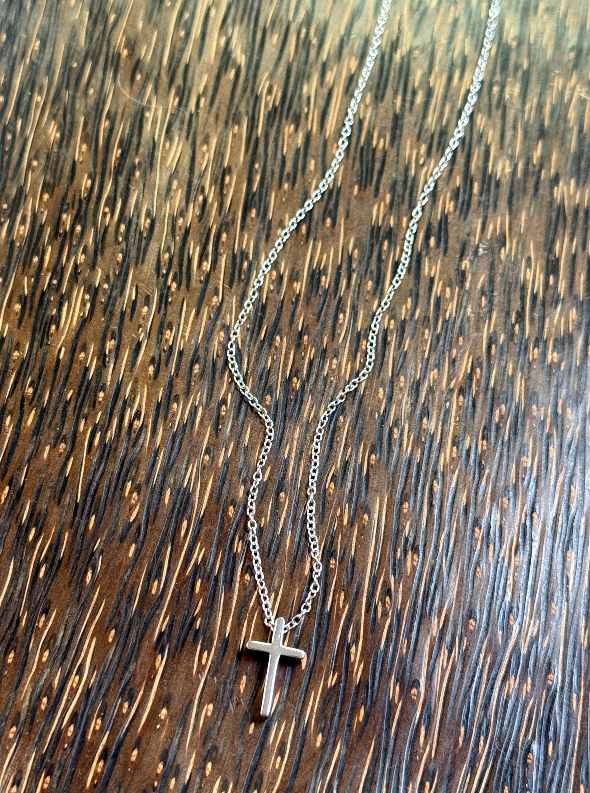 Sterling Silver necklace with a cross pendant on a wooden surface