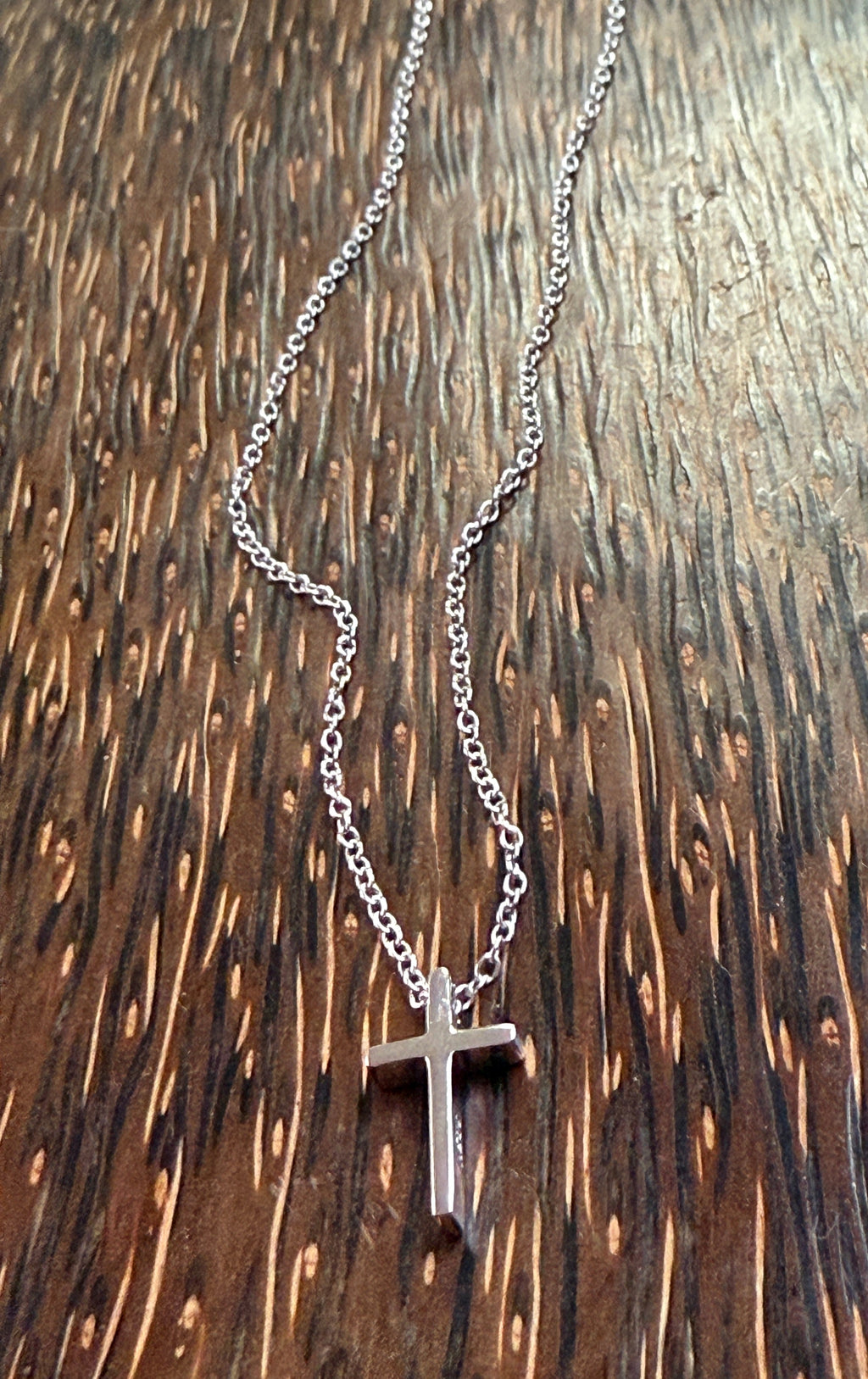 Silver cross necklace on a wooden surface