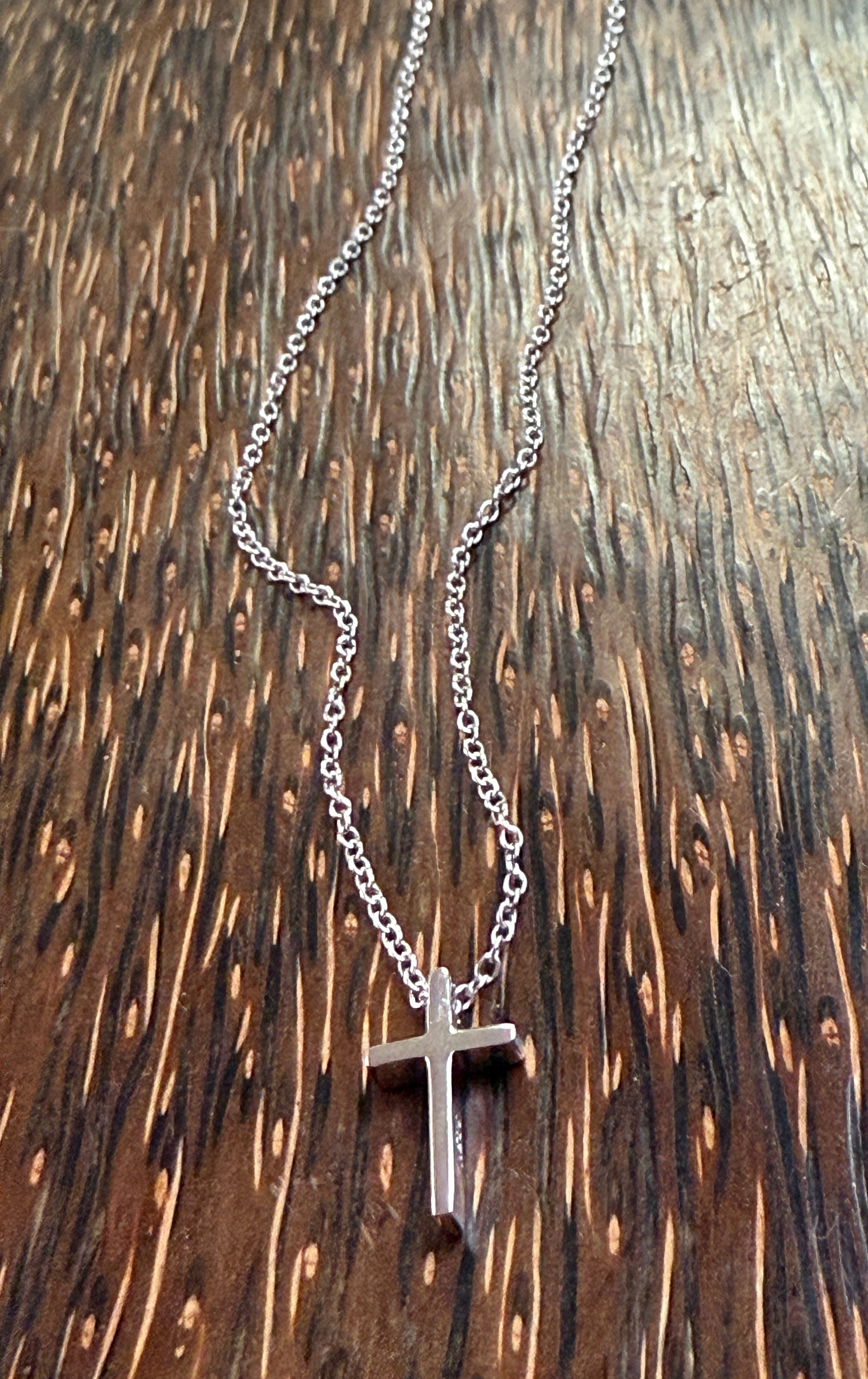 Silver cross necklace on a wooden surface