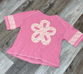 Pink t-shirt with a floral design on a wooden floor