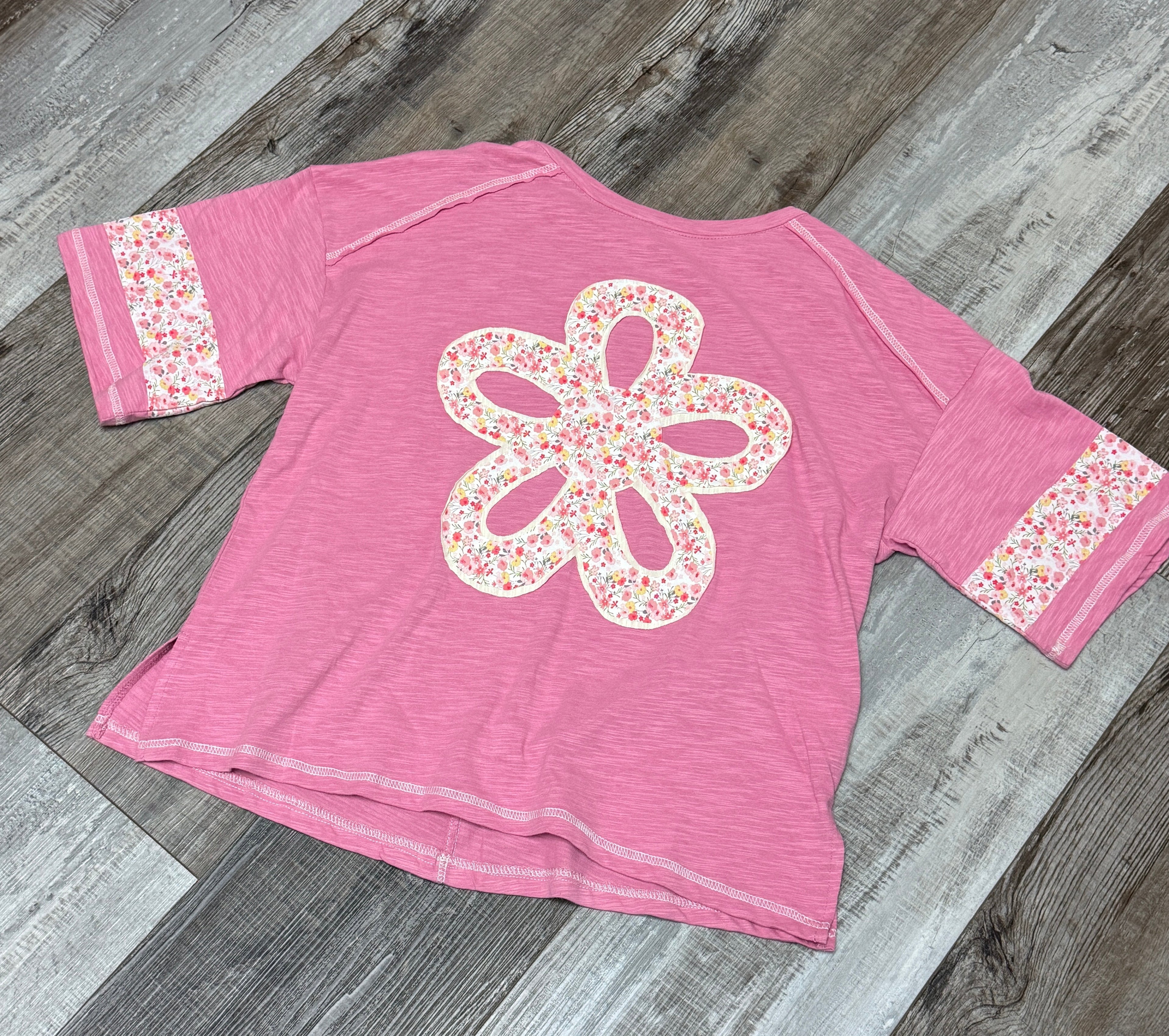 Pink t-shirt with a floral design on a wooden floor