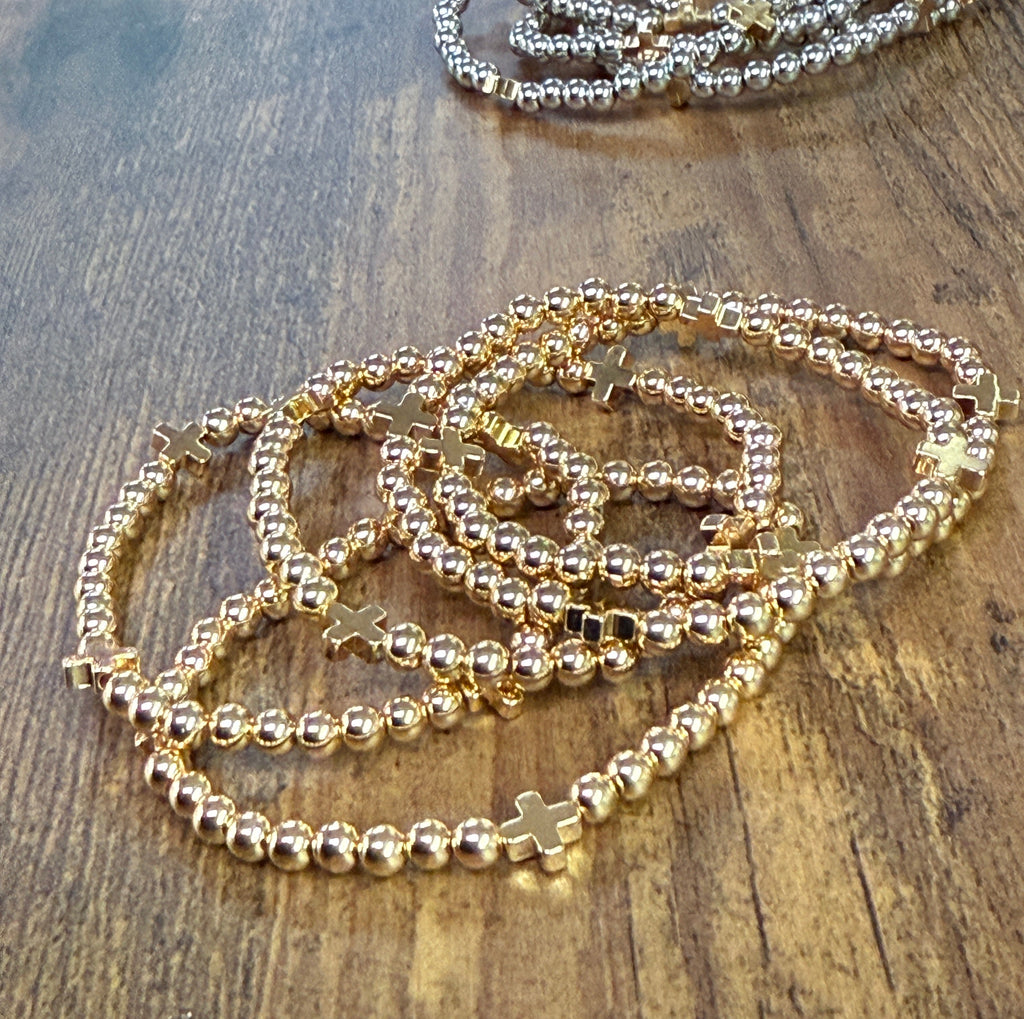 Gold beaded bracelets on a wooden surface
