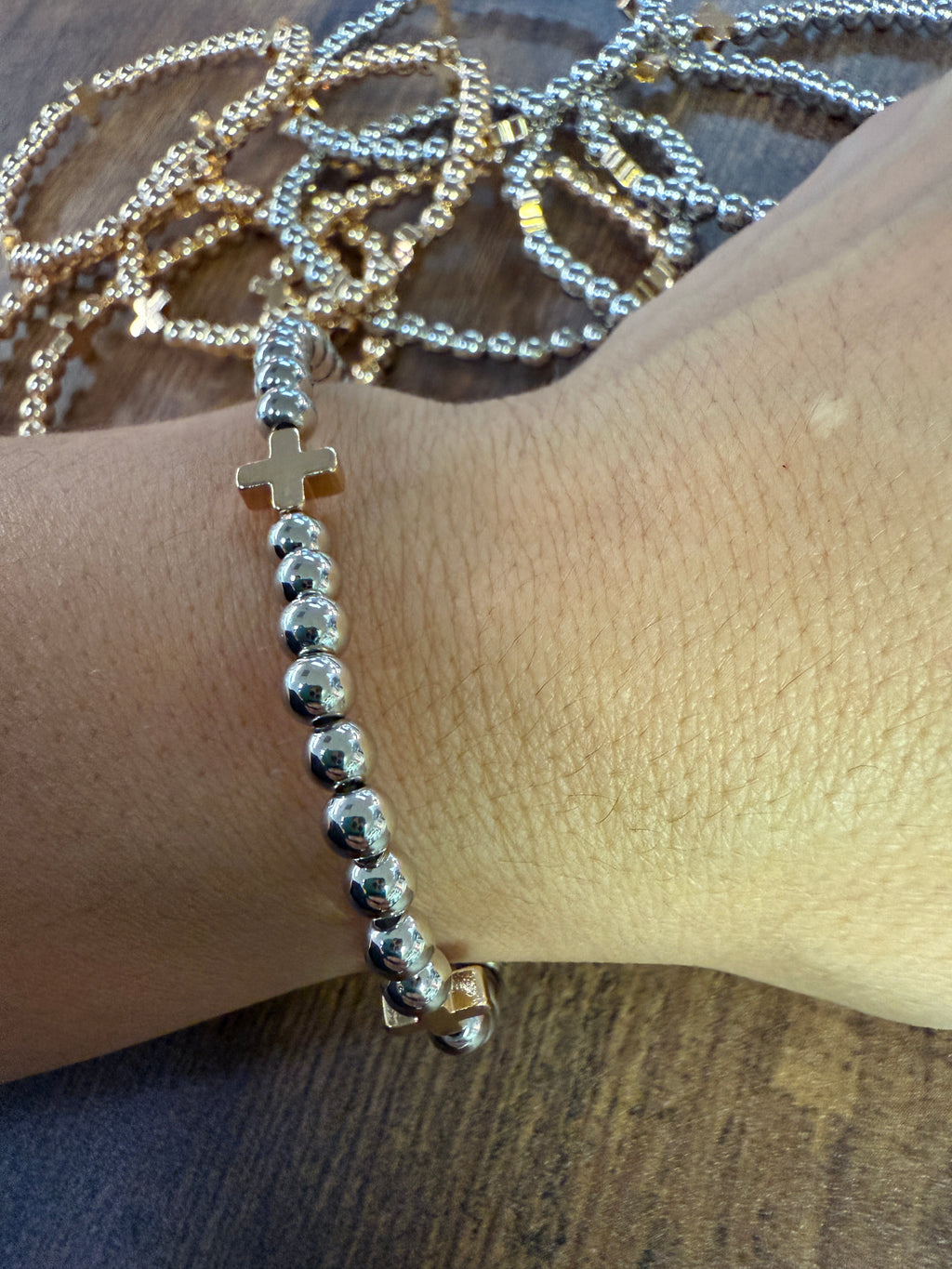 Silver beaded bracelet on a wrist with a wooden surface in the background