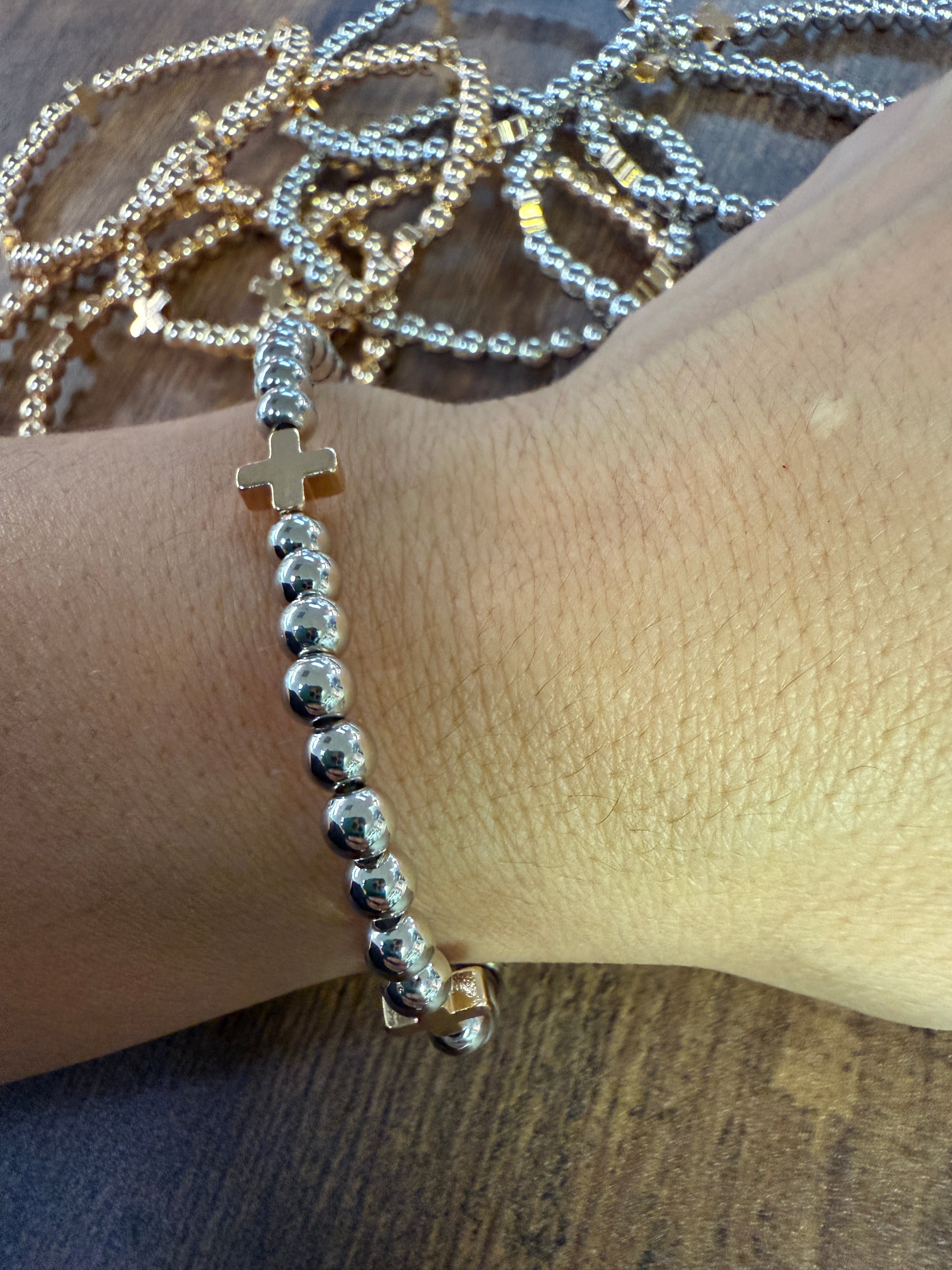 Silver beaded bracelet on a wrist with a wooden surface in the background