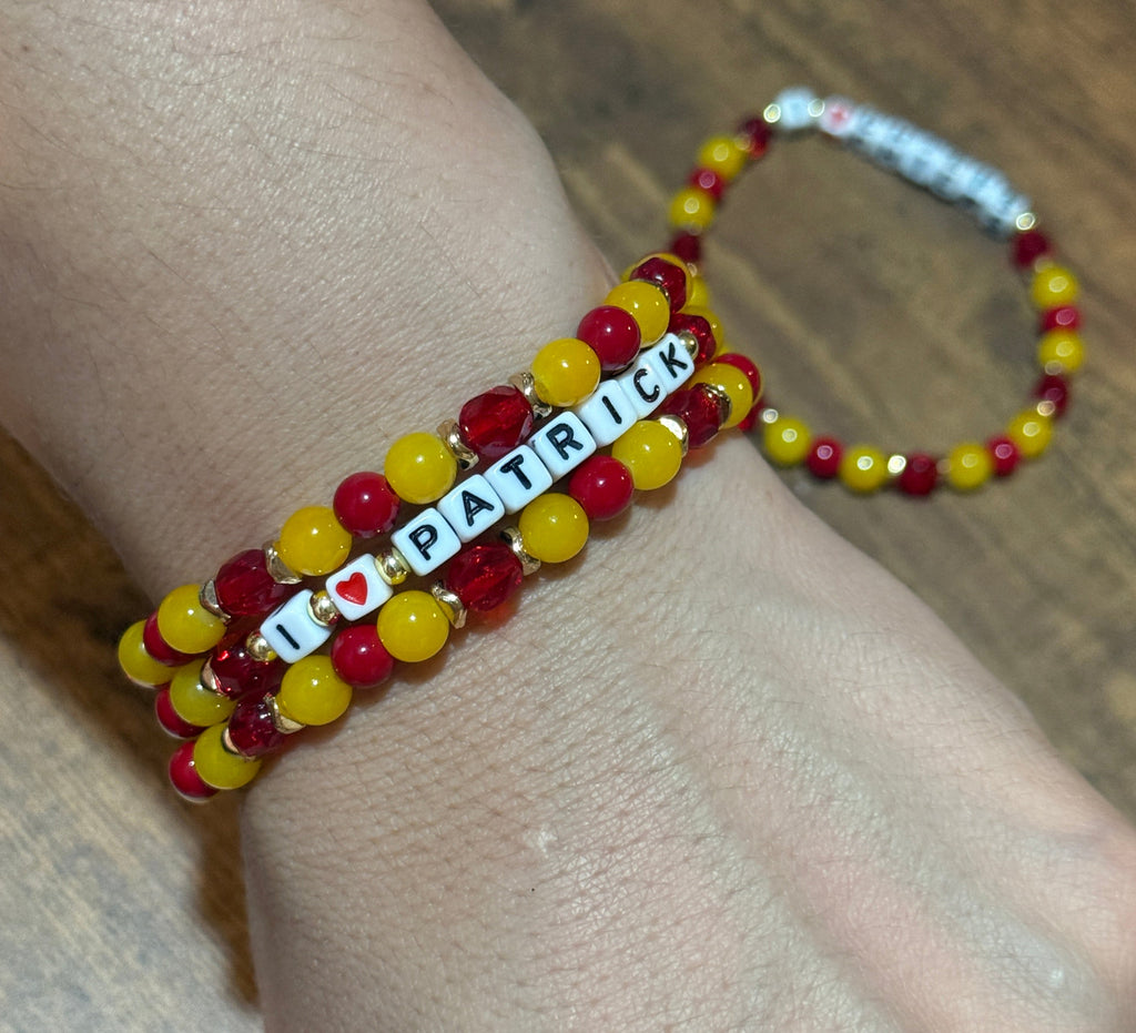 Beaded bracelet with letter beads on a wrist against a wooden surface