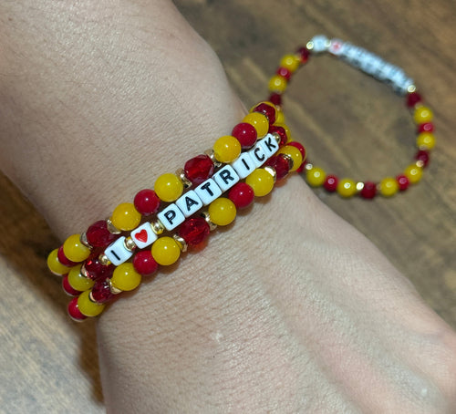 Beaded bracelet with letter beads on a wrist against a wooden surface