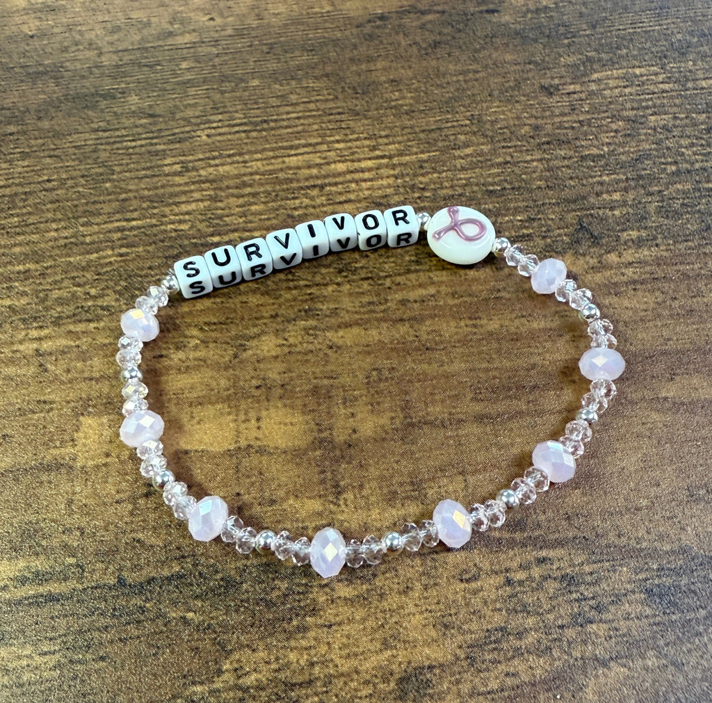 Beaded bracelet with 'SURVIVOR' beads on a wooden surface