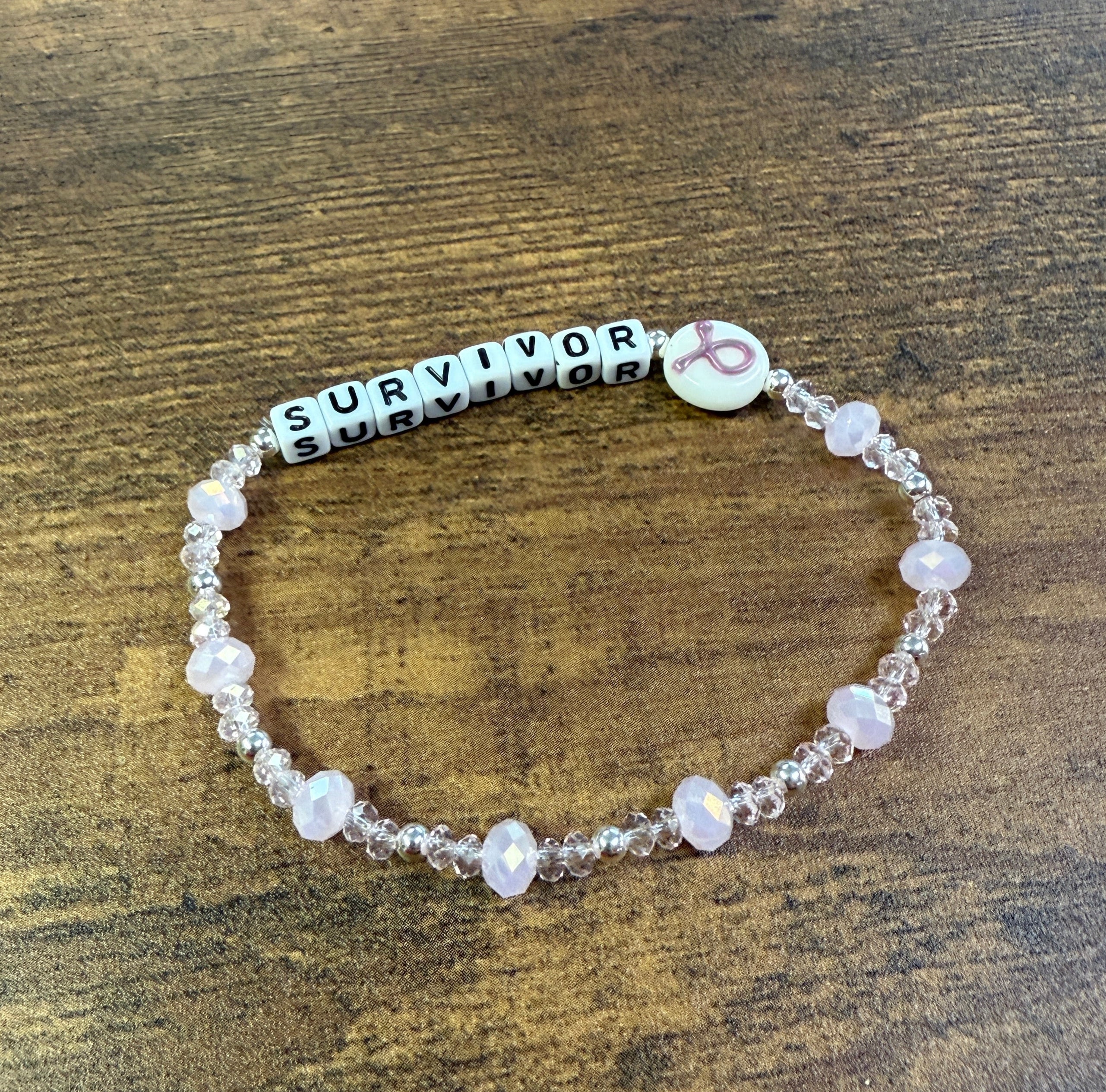 Beaded bracelet with 'SURVIVOR' beads on a wooden surface