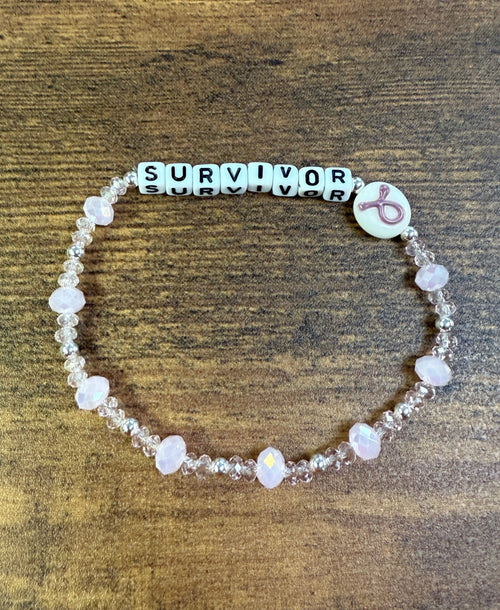Beaded bracelet with 'SURVIVOR' on a wooden surface