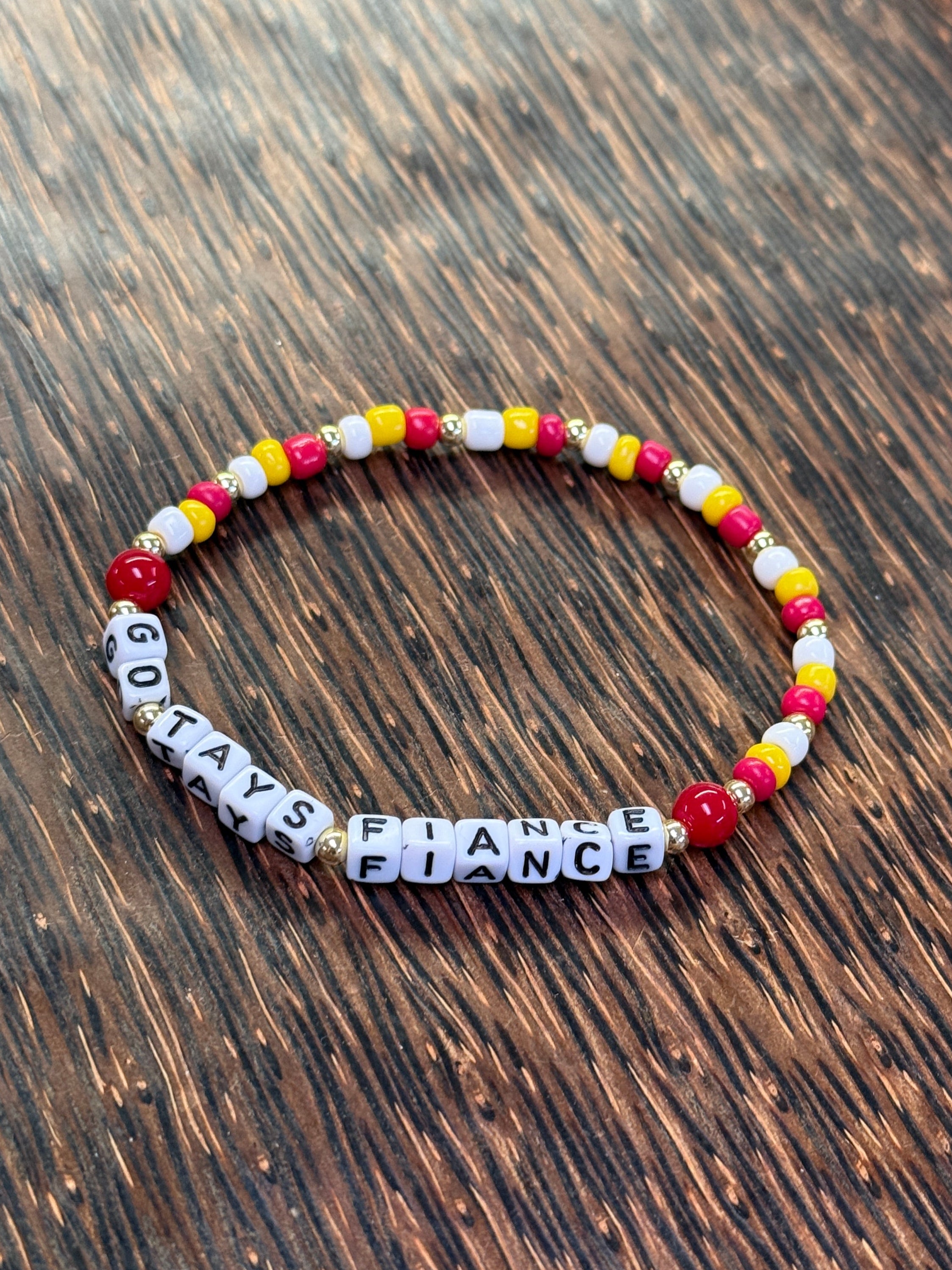 "Go Tays Fiance" Beaded bracelet with letter beads on a wooden surface