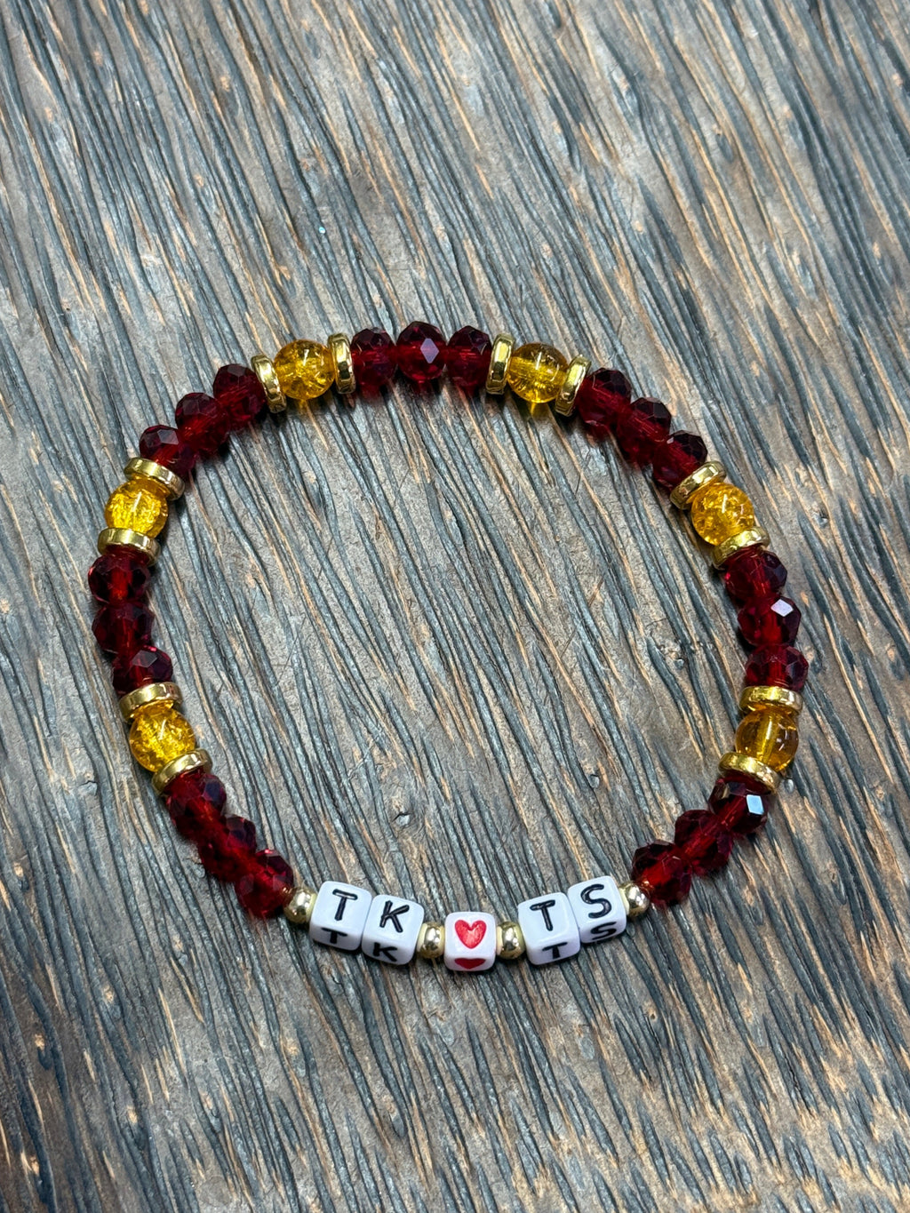 Beaded bracelet with colorful beads and heart-shaped charms on a wooden surface