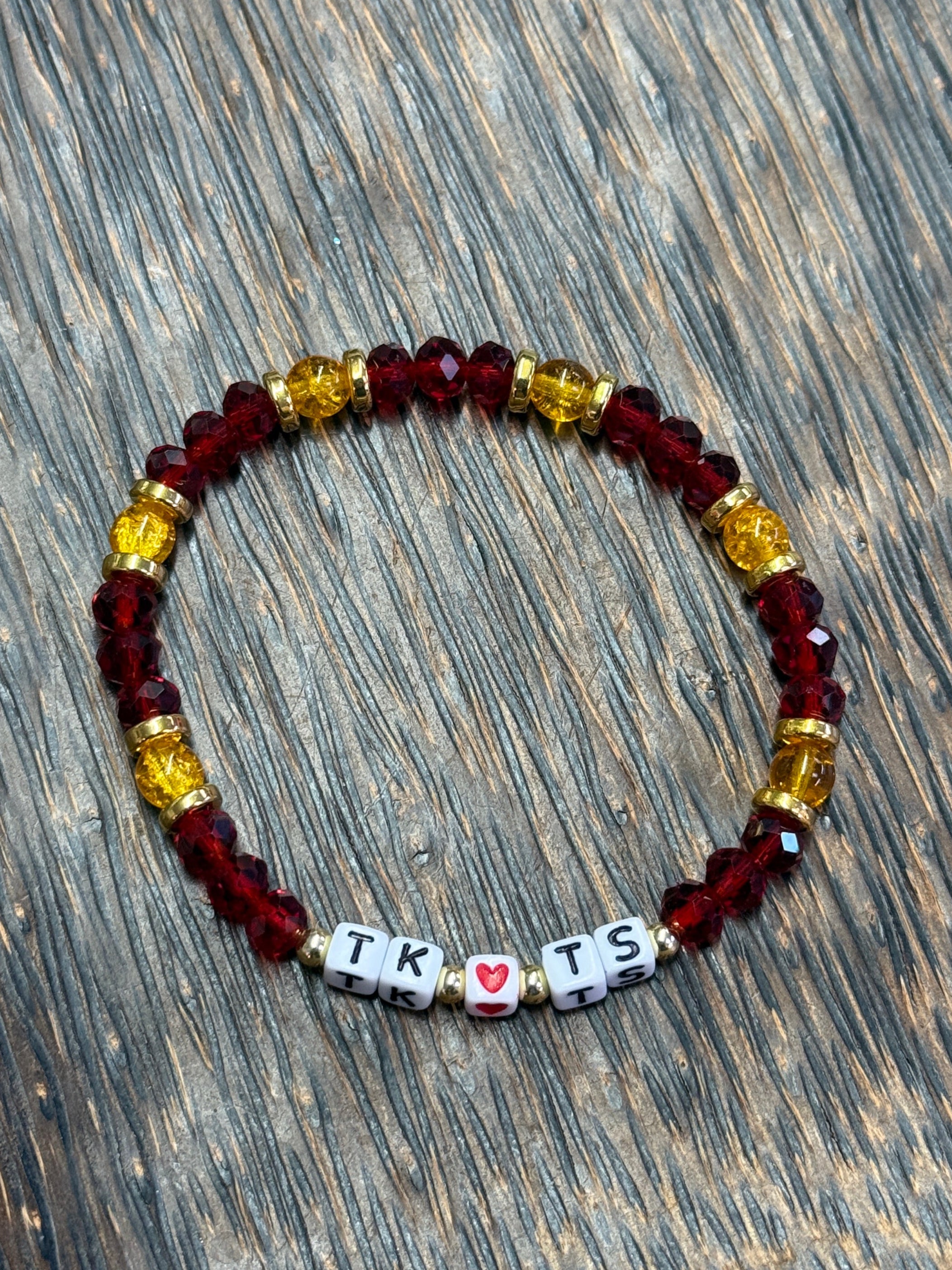 Beaded bracelet with colorful beads and heart-shaped charms on a wooden surface