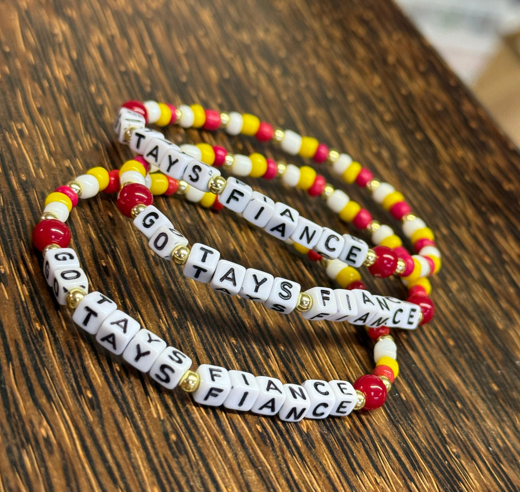 Three beaded bracelets with text on a wooden surface
