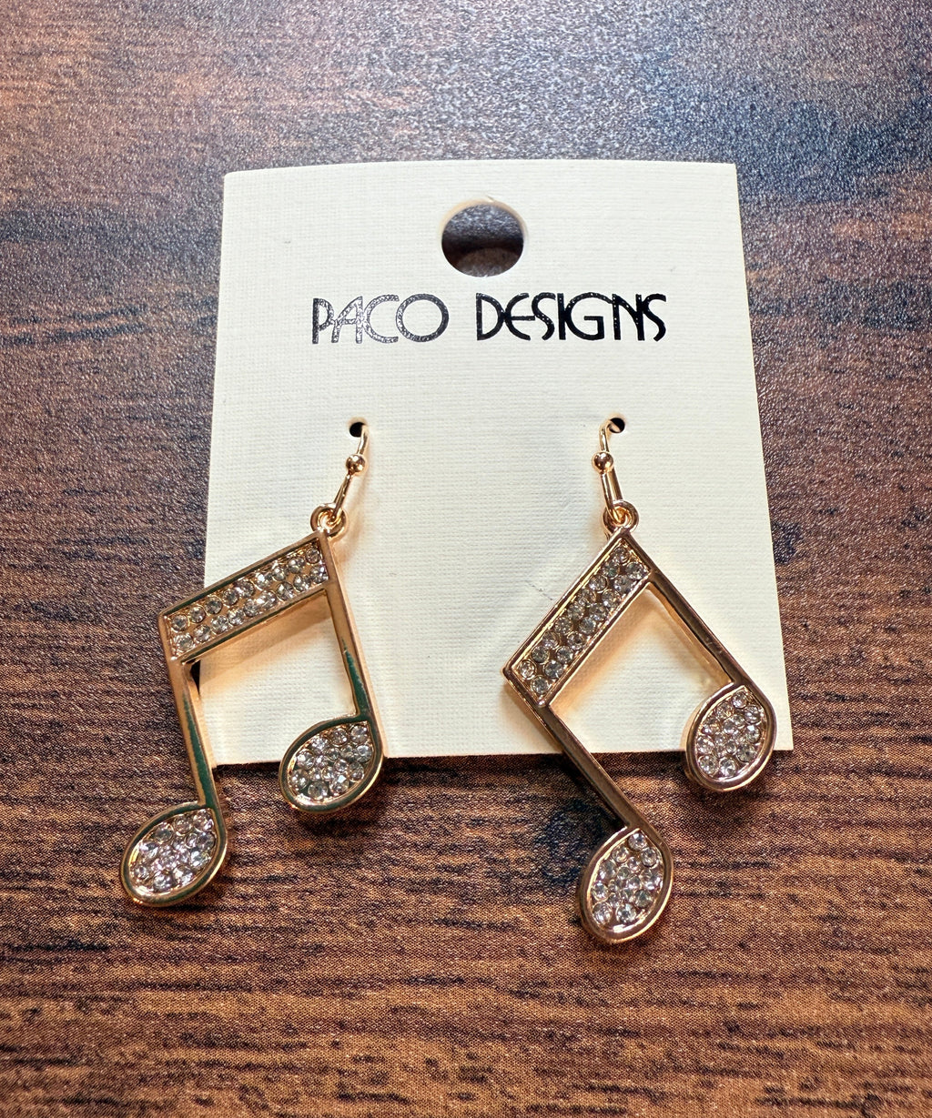 Gold music note earrings with  rhinestones on a Paco Designs card against a wooden background