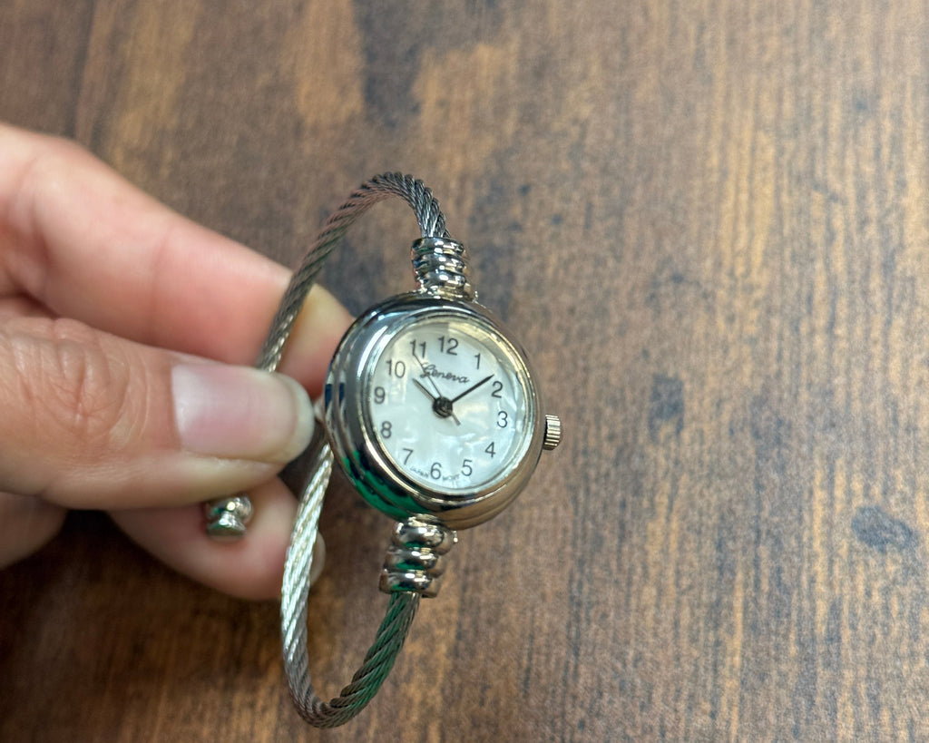 Vintage-style wristwatch held by a hand on a wooden surface