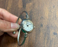 Vintage-style wristwatch held by a hand on a wooden surface