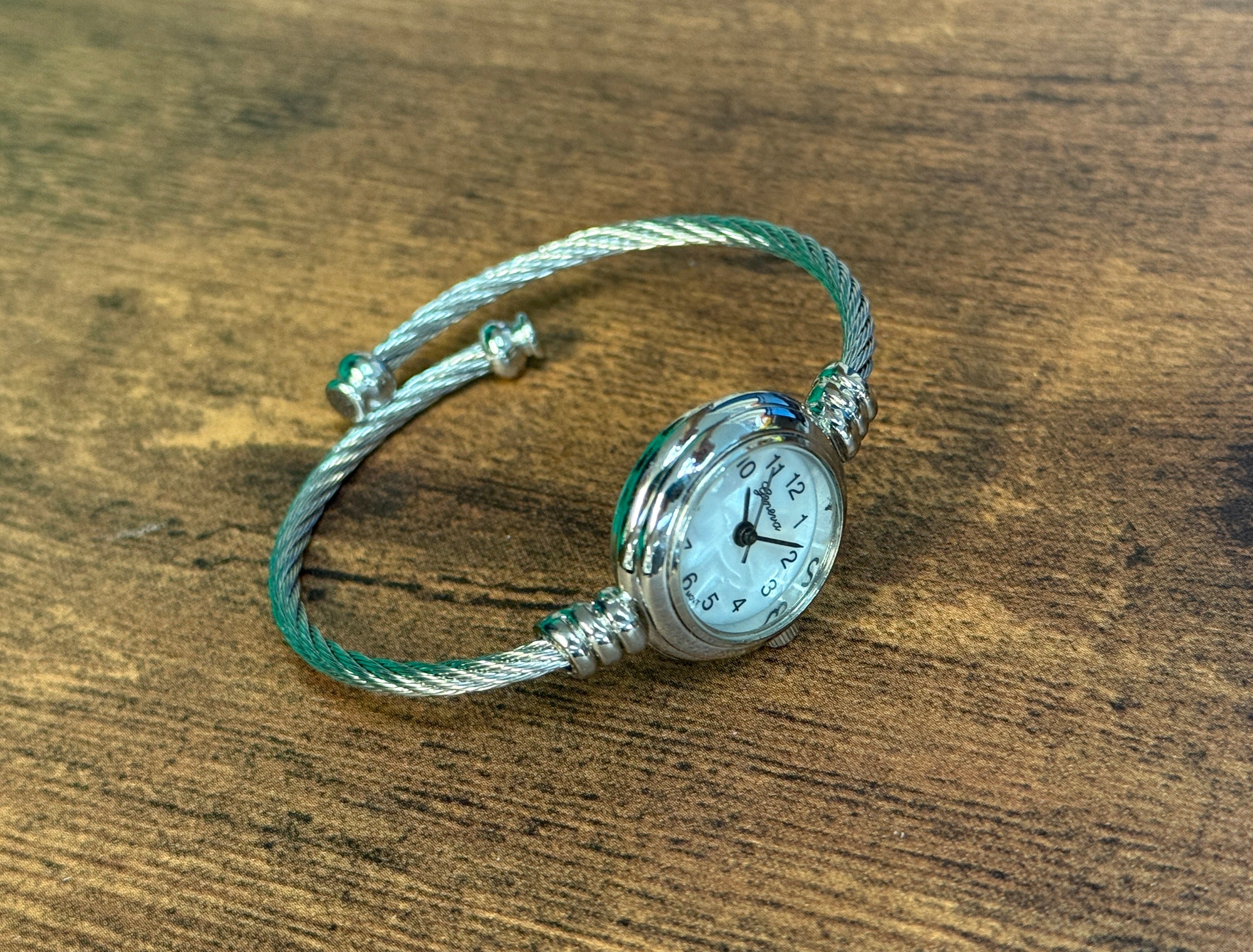 Silver watch with a braided strap on a wooden surface