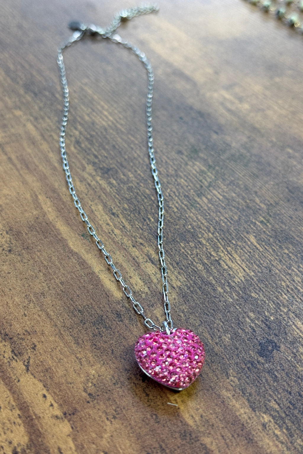Necklace with a pink heart-shaped pendant on a wooden surface