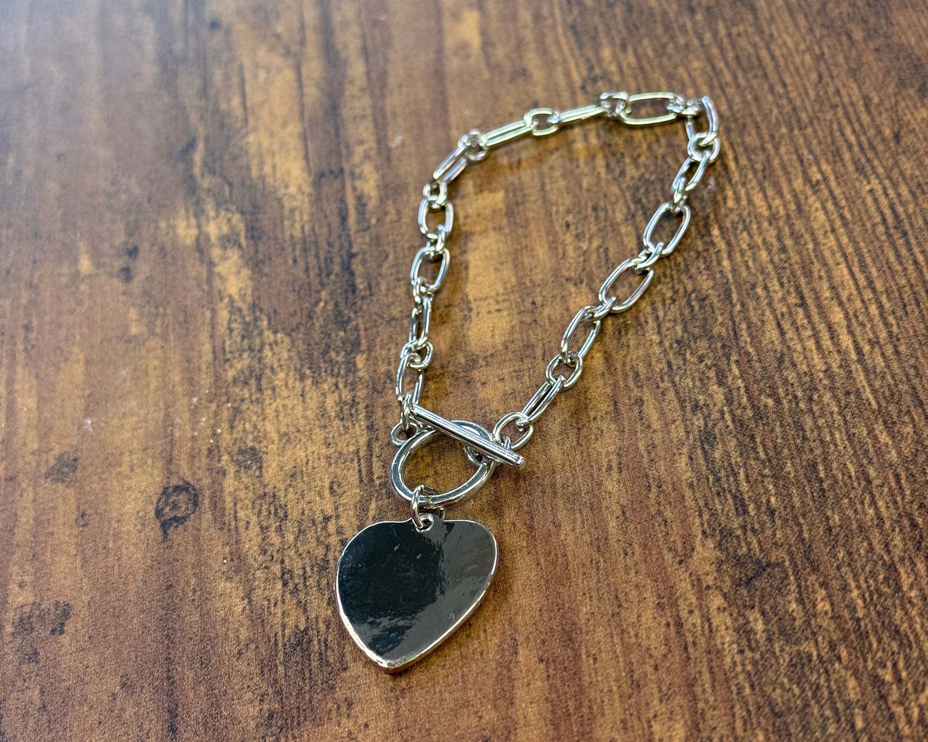Heart-shaped metal charm on a chain against a wooden background