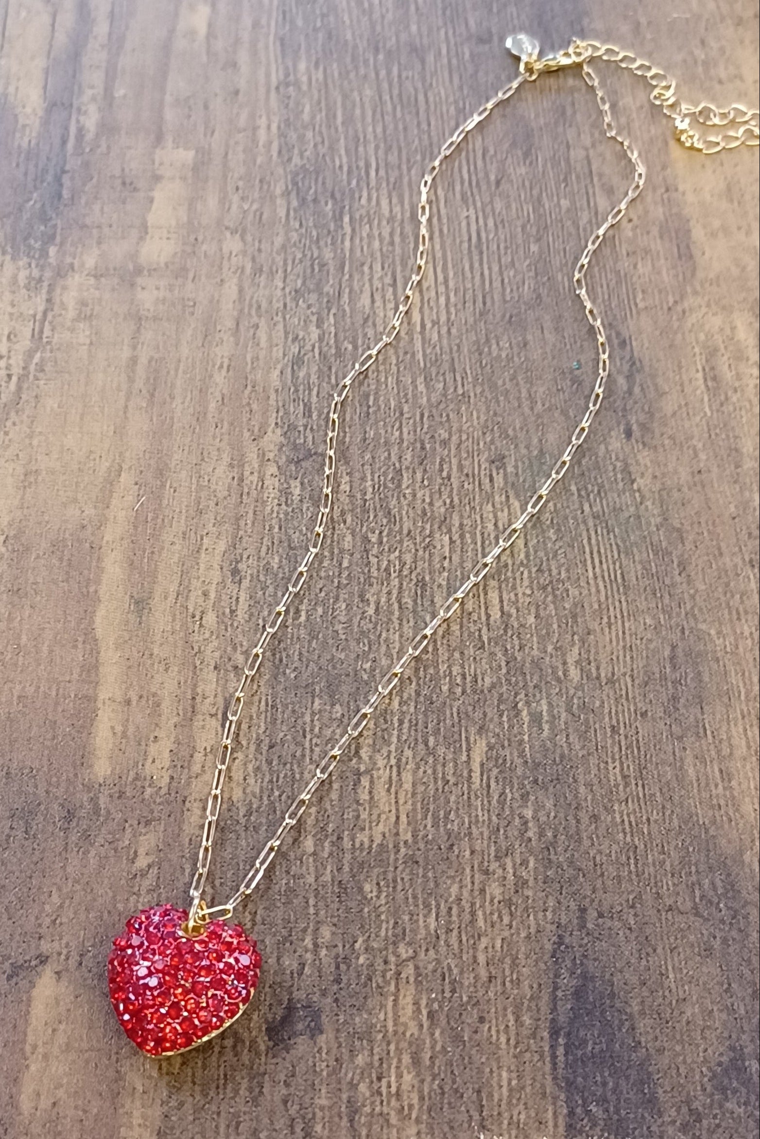 Necklace with a red heart pendant on a wooden surface